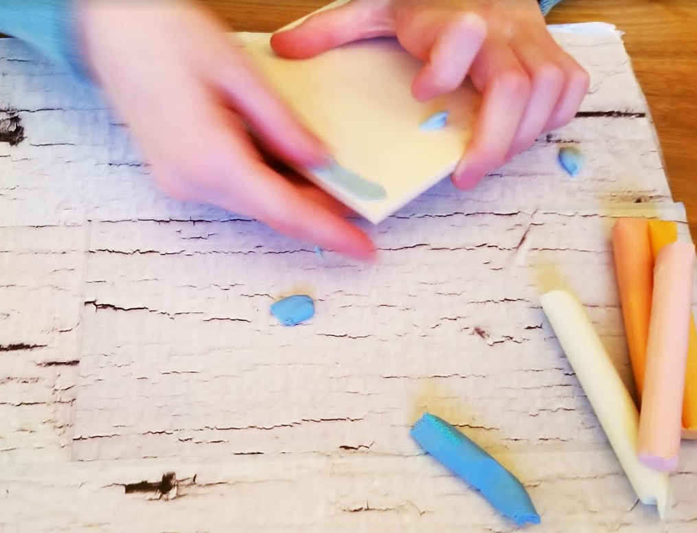 spring craft for kindergarten shows a child smearing plasticine on a wooden square.