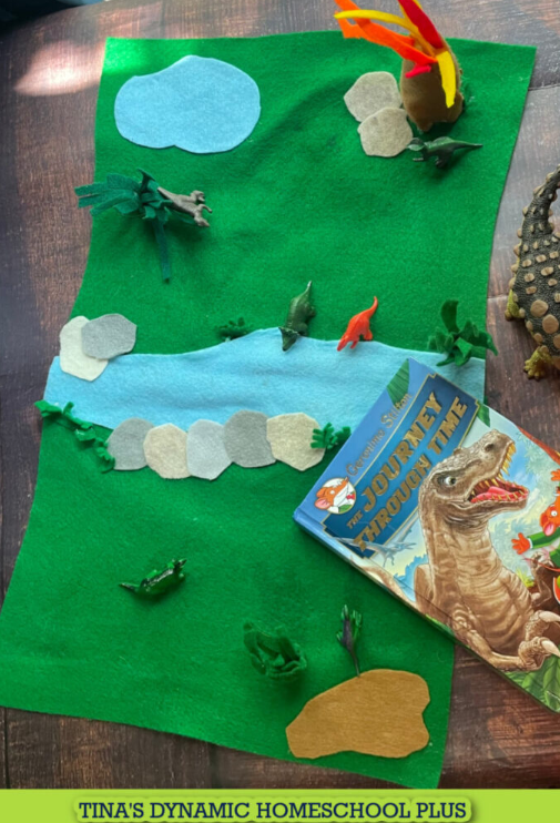 small world play shows a felt play mat with dinosaur pieces and a book.