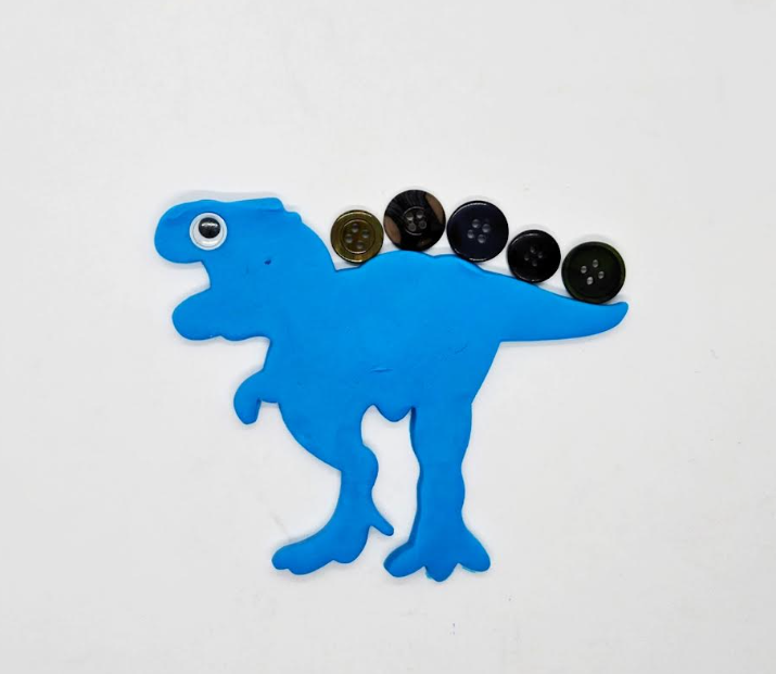 dinosaur created from playdough and a googly eye and buttons.