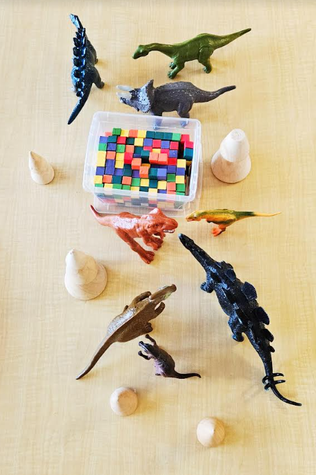 dinosaur activities for kids shows dinosaur figures and wooden blocks.