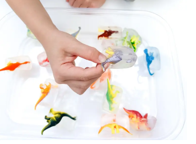 dinosaur activities for kid shows a child holding a dinosaur figure and other dinos frozen in ice.