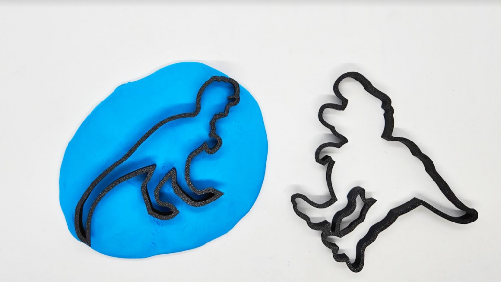 dinosaur sensory play shows a ball of playdough and two dinosaur cookie cutters.