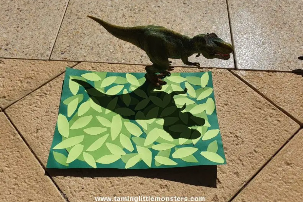 dinosaur activities for kids shows a dinosaur outside creating a shadow on a page of leaves.