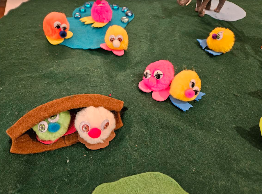 arts and crafts for kids shows colorful pompom critters on a felt mat.