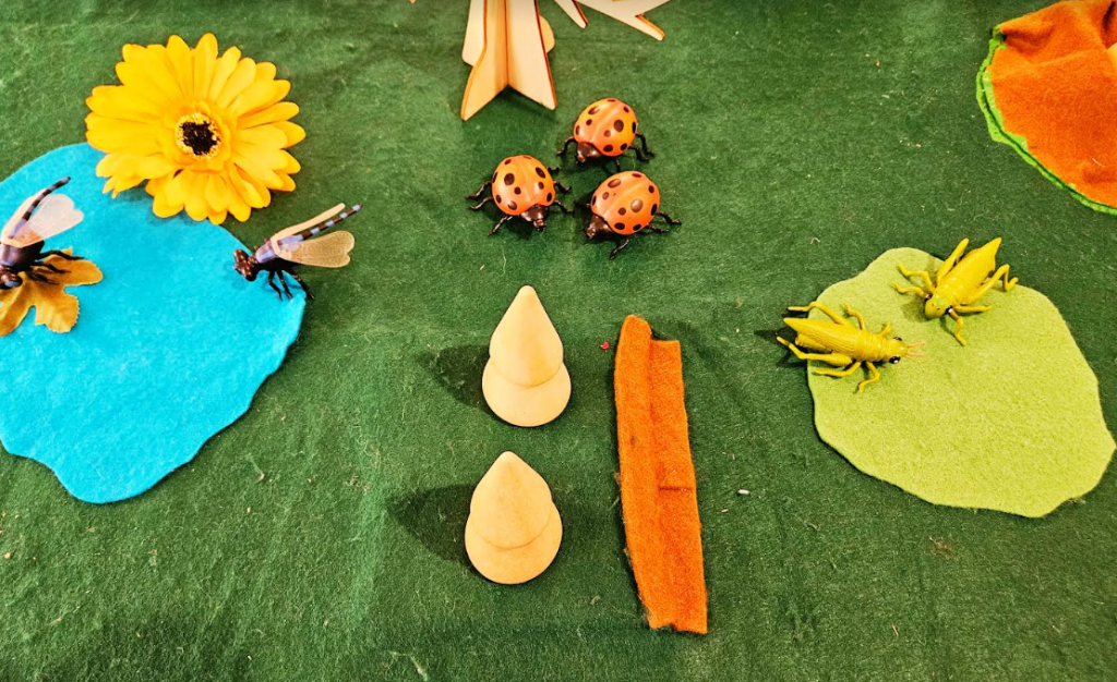 preschool centers shows more flowers, plastic bugs on a large felt mat.