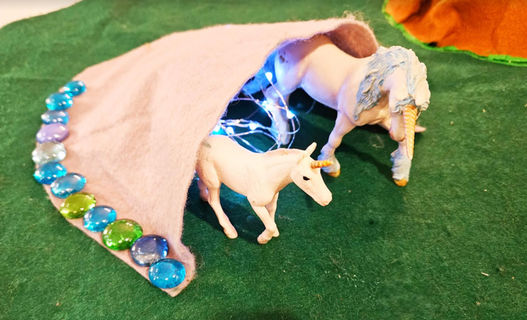 small world play shows a cave with unicorn figures and lights inside.