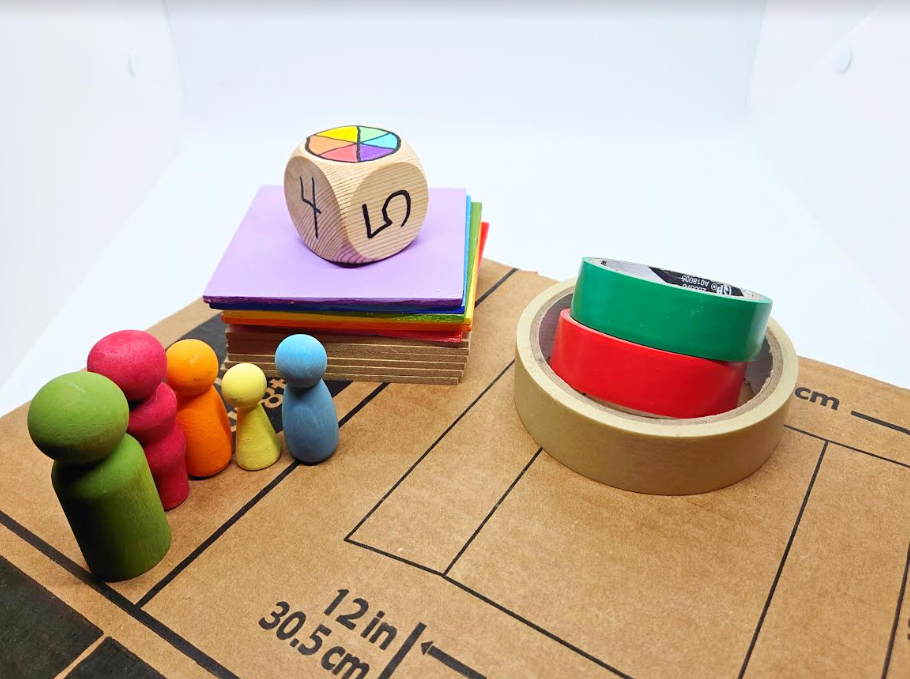 math coding game shows wooden people, tape, a dice, wooden squares and a board.