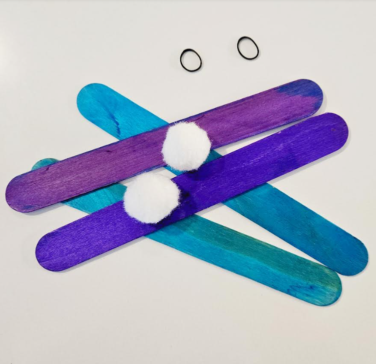 counting game for kindergarten shows four large popsicle sticks, pompoms and small elastics.