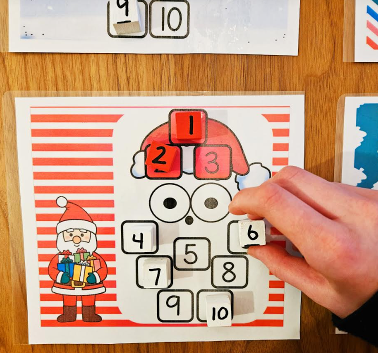 free activity shows a child putting a number 6 on Santa's beard on a printable.