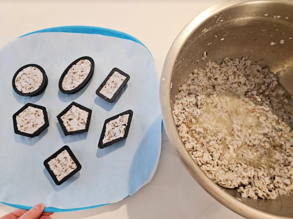 diy recycled seed bombs shows seven seed bombs in shape cookie cutters and a bowl of paper pulp.