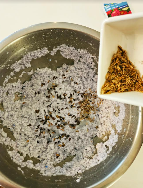 diy recycled seed bombs shows a bowl of paper pulp with seeds being added.