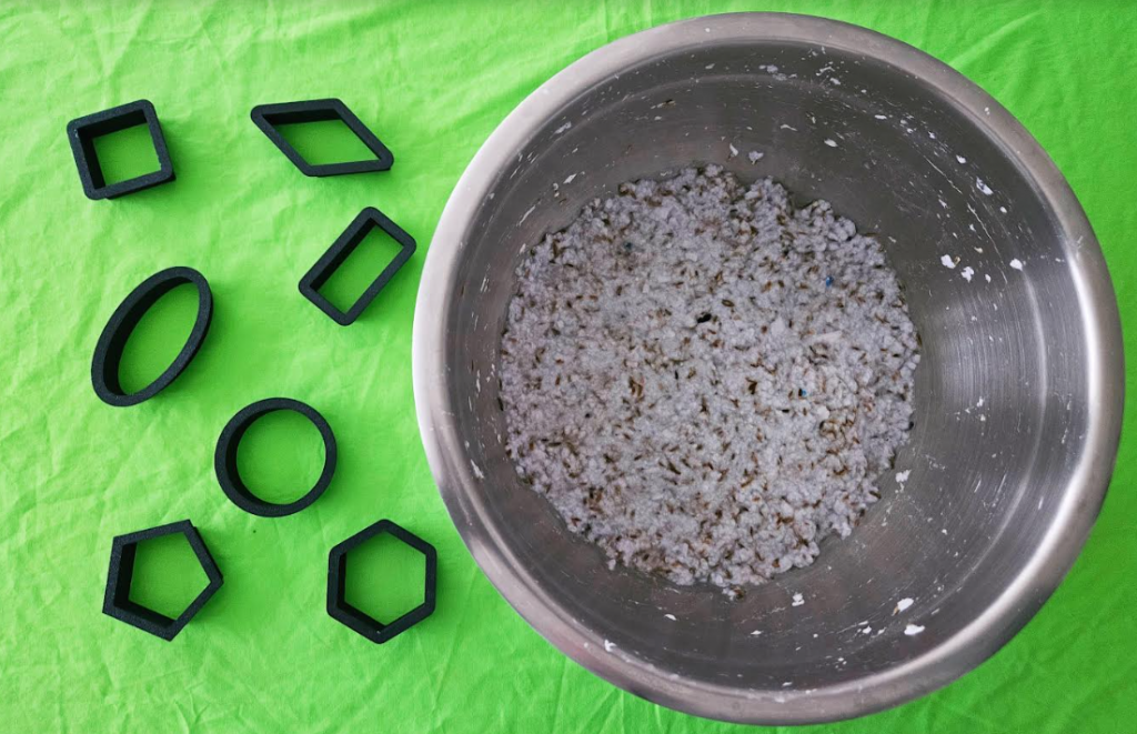 diy recycled seed bombs shows a bowl of paper pulp and 2d shape cookie cutters.