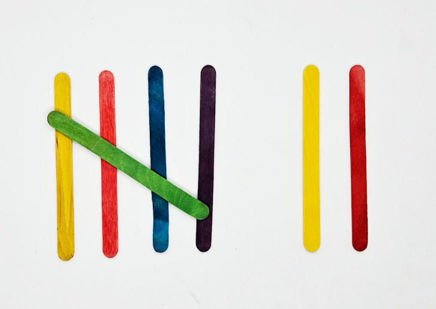 preschool math shows seven popsicle sticks making tally marks.