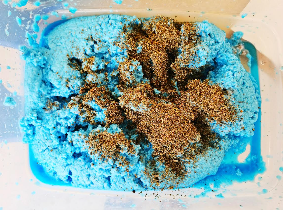diy Fathers Day gift idea shows a large bin of shredded paper with blue food coloring and seeds being mixed in.