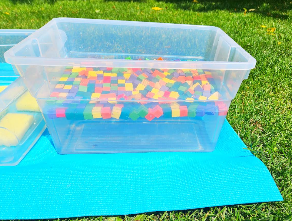 summer outdoor activity shows a bin with water and wooden cubes floating on top.
