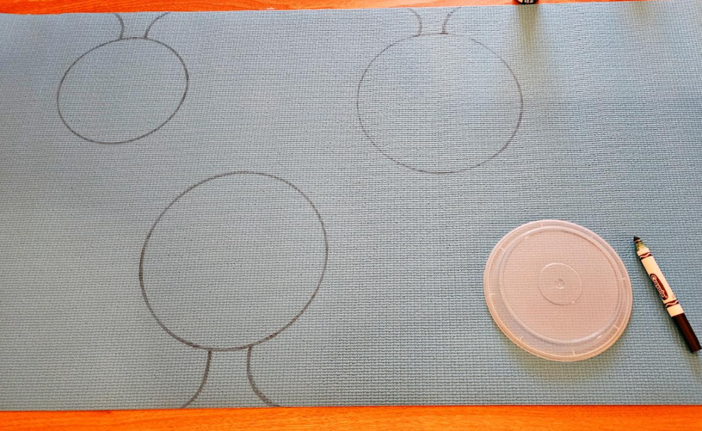 yoga mat shows a rolled out mat with three circles for faces and a neck drawn.