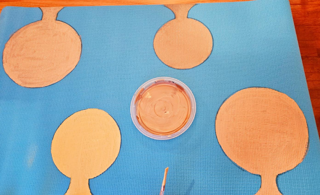 self portrait art project for young kids shows a yoga mat with four faces painted on it.