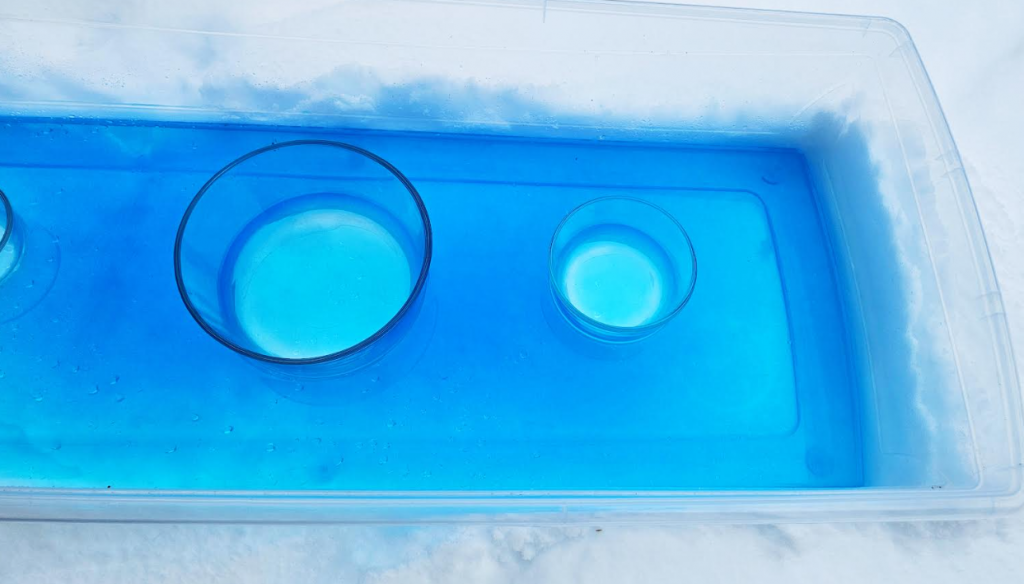 DIY winter sensory tray shows water frozen in a bin.
