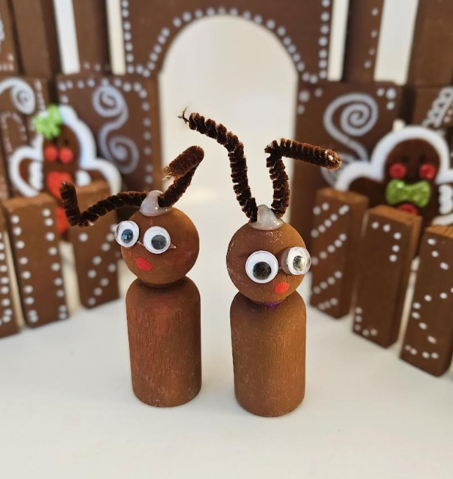 diy gingerbread house with blocks shows two reindeer looking critters made from wooden peg people.