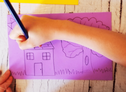 easy printmaking craft for kids shows a child drawing a house on a piece of foam paper.