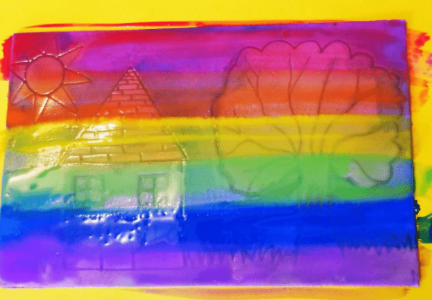 easy printmaking craft for kids shows streaks of rainbow paint across a piece of foam.