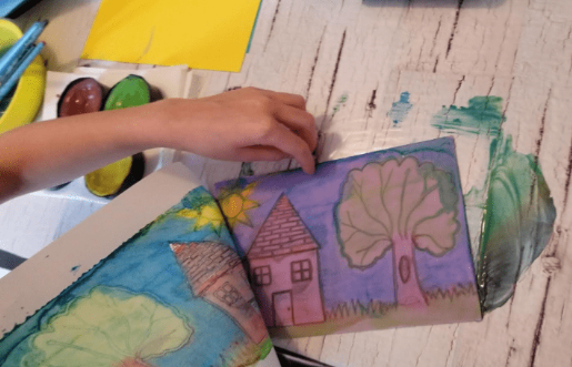 printmaking project for kids shows a child peeling cardstock paper off a foam page.