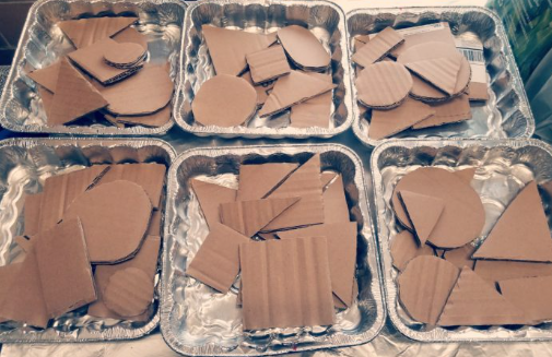art project for kindergarten shows six containers with 2d shapes cut out of cardboard.